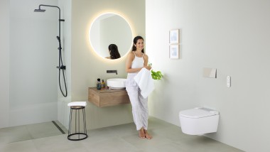 Woman leaning on a washbasin in a bathroom with Geberit Sigma70 flush button